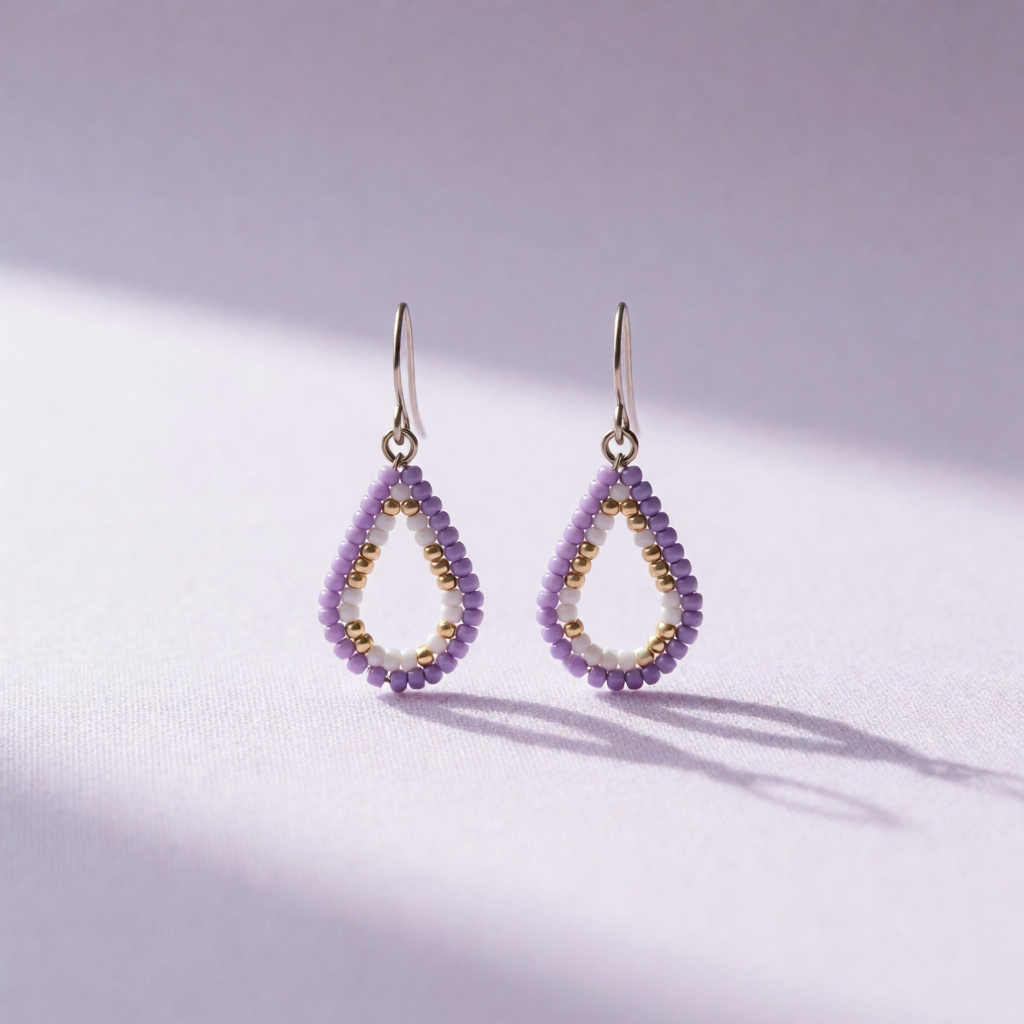 A pair of purple beaded teardrop earrings on a lavender backdrop