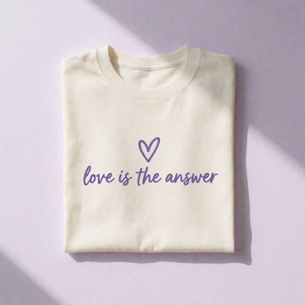 A cream t-shirt screen printed with a heart and the words love is the answer